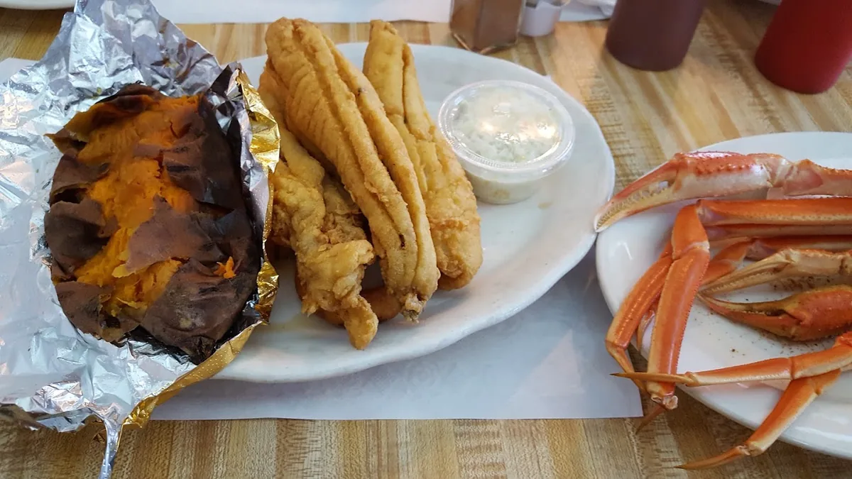 Fried flounder filets, snow crab legs, and a baked sweet potato